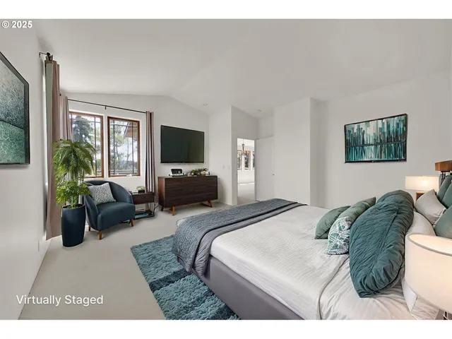 a bedroom with a bed a couch and a flat tv screen on the dresser