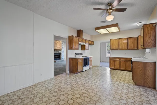 a large kitchen with stainless steel appliances a stove a sink and a refrigerator