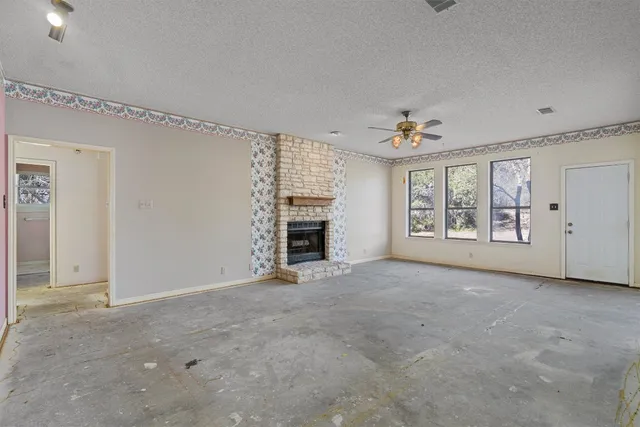 an empty room with windows and fireplace