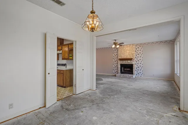 an empty room that has a fireplace and a chandelier