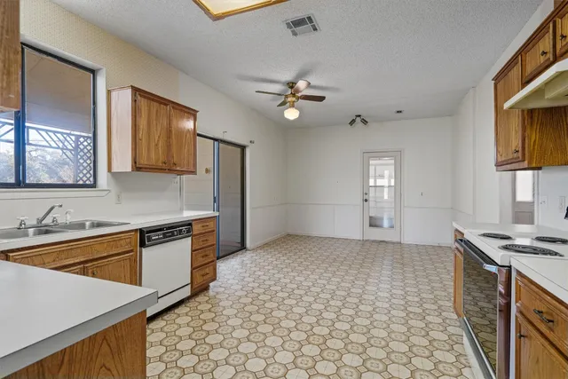 a kitchen with stainless steel appliances granite countertop a sink a stove a refrigerator cabinets and living room view