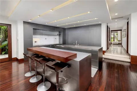 a dining hall with stainless steel appliances granite countertop a table chairs and wooden floors