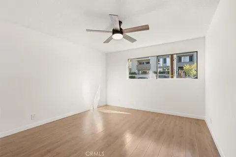 an empty room with wooden floor ceiling fan and windows
