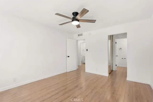 a view of empty room with wooden floor and ceiling fan
