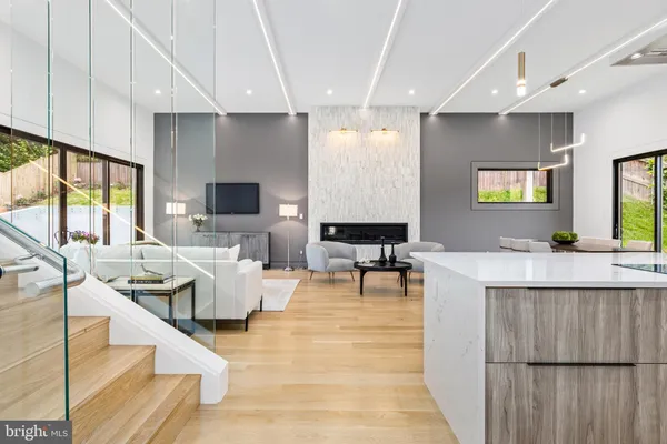 a living room with couches a flat tv screen and a dining table with wooden floor