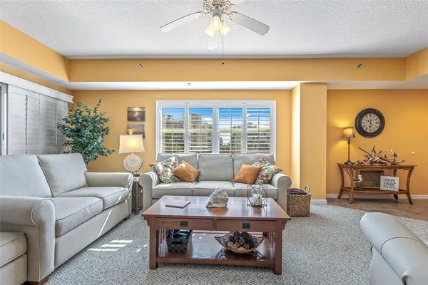 a living room with furniture ceiling fan and a large window