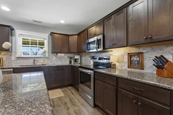 a kitchen with stainless steel appliances granite countertop stove a sink dishwasher and cabinets with wooden floor