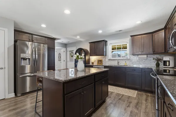 a kitchen with kitchen island granite countertop a sink stove and refrigerator