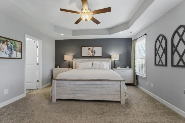 a bedroom with a bed a painting on the wall and a chandelier