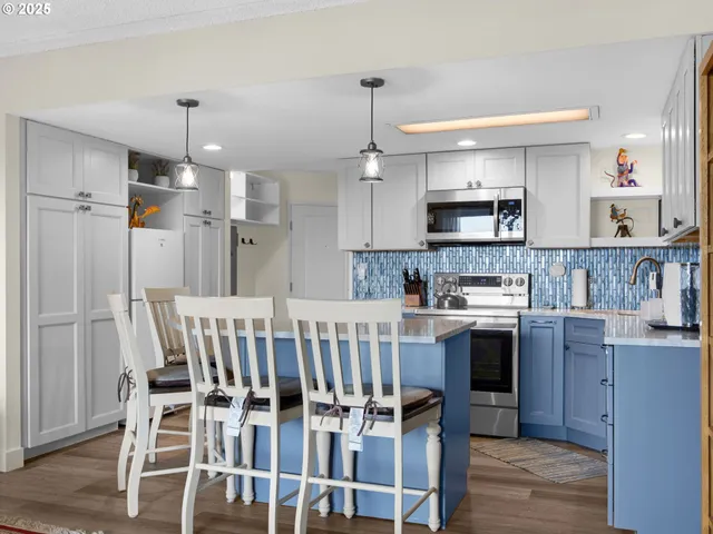 a kitchen with kitchen island a stove a refrigerator and a dining table with wooden floor