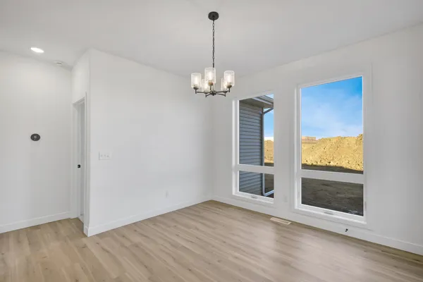 an empty room with wooden floor cabinet and windows
