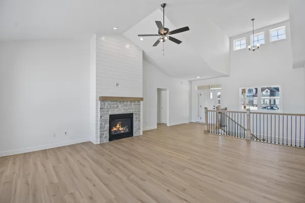 a view of an empty room with wooden floor fireplace and a window