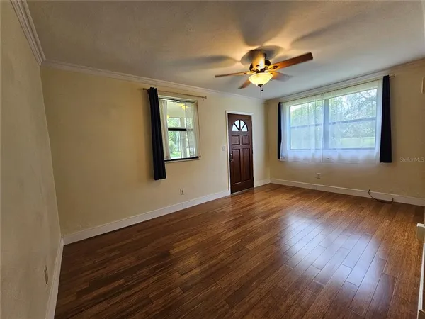 a view of a livingroom with wooden floor and a ceiling fan