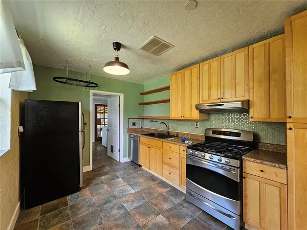 a kitchen with granite countertop a stove cabinets and refrigerator