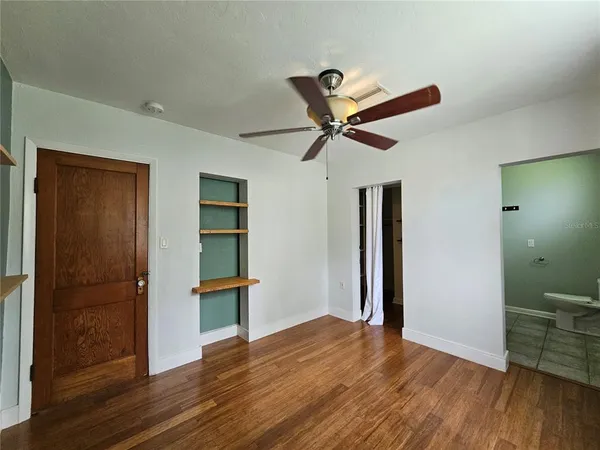 a view of room with wooden floor and a ceiling fan