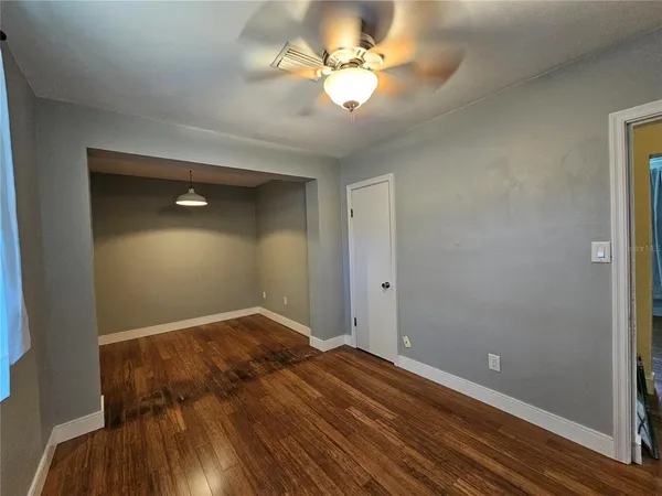 a view of a room with wooden floor and a ceiling fan