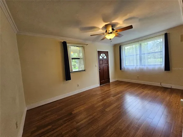 a view of empty room with wooden floor and fan