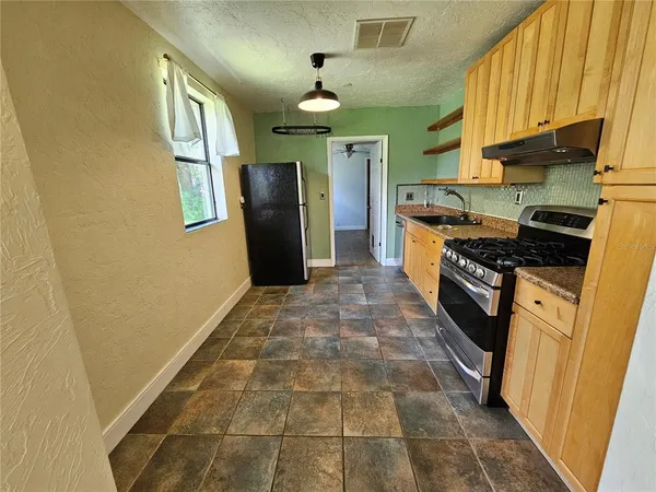 a kitchen with stainless steel appliances granite countertop a refrigerator a stove and a sink