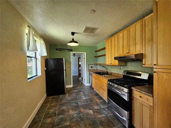 a kitchen with stainless steel appliances granite countertop a refrigerator a sink and wooden cabinets