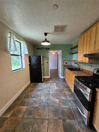 a kitchen with granite countertop a stove a sink and a refrigerator