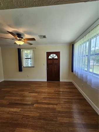 a view of an empty room with window and wooden floor