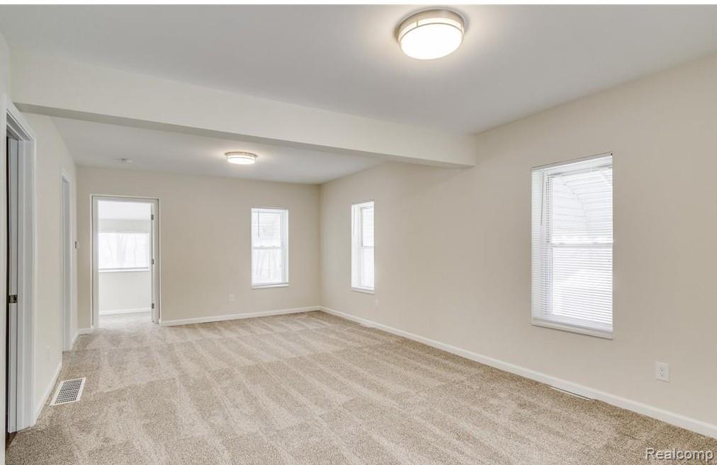 2365 Welch Road Walled Lake, MI 48390 - Photo 2 of 14 Spacious interior room featuring light-colored walls, patterned carpeting, and multiple windows with blinds