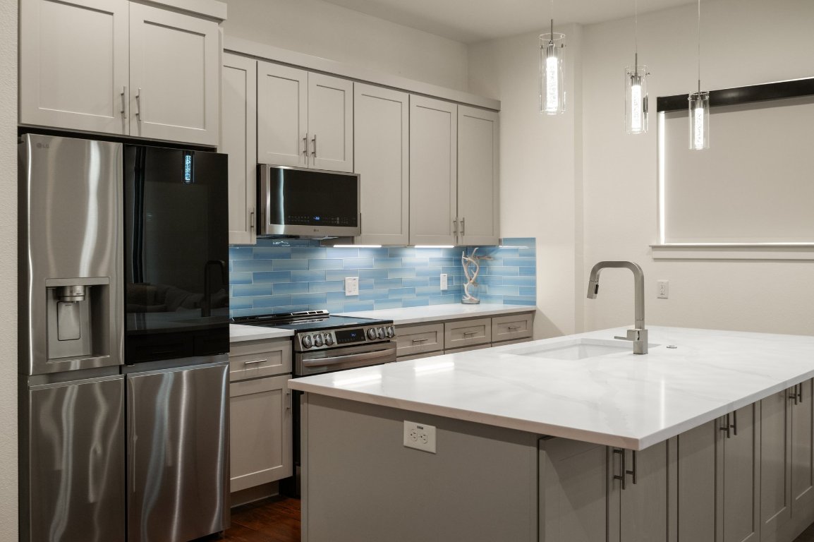 1101 Ivean Pearson Road, Unit E201 Leander, TX 78645 - Photo 5 of 20 a kitchen with kitchen island a sink stainless steel appliances and cabinets