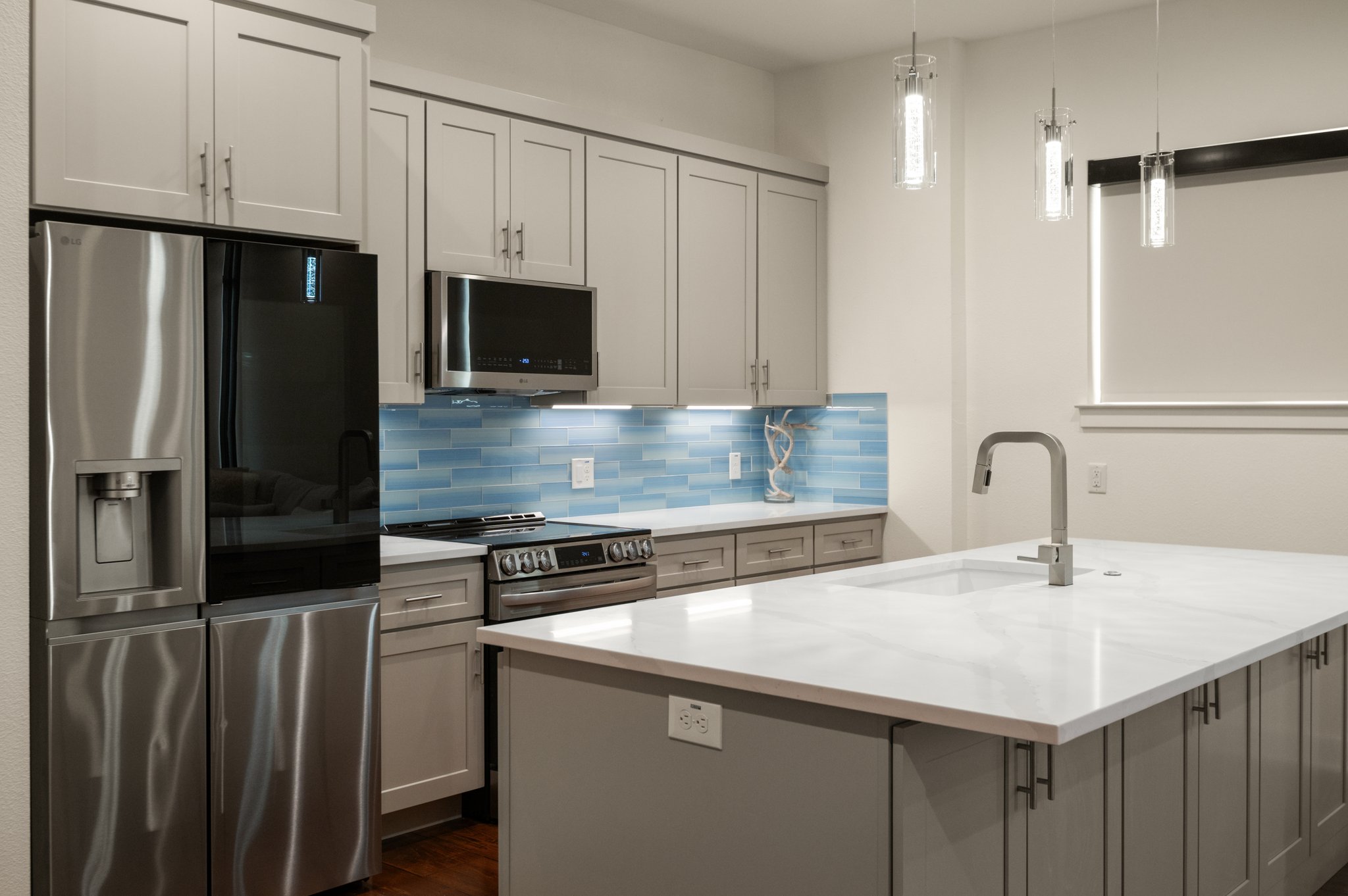 1101 Ivean Pearson Road, Unit E201 Leander, TX 78645 - Photo 5 of 20 Kitchen featuring stainless steel appliances, a sink, backsplash, a center island with sink, and pendant lighting
