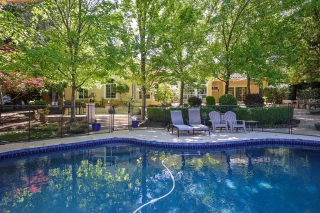 a view of swimming pool with outdoor seating and trees in the background