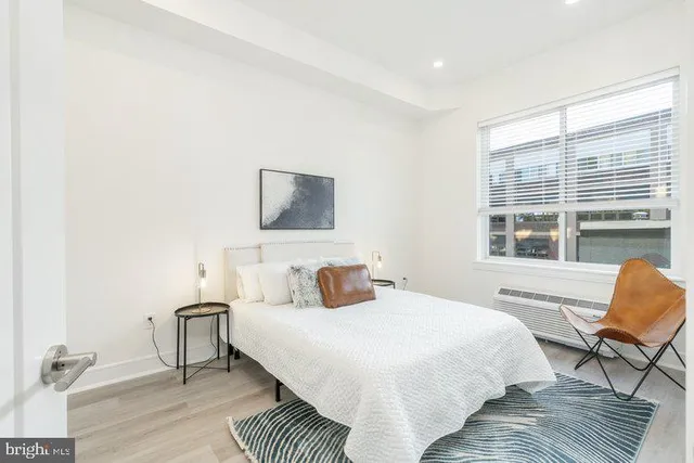 a bedroom with a bed a chair and a large window