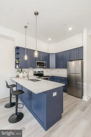 a kitchen with stainless steel appliances kitchen island granite countertop a sink a refrigerator and a counter top space