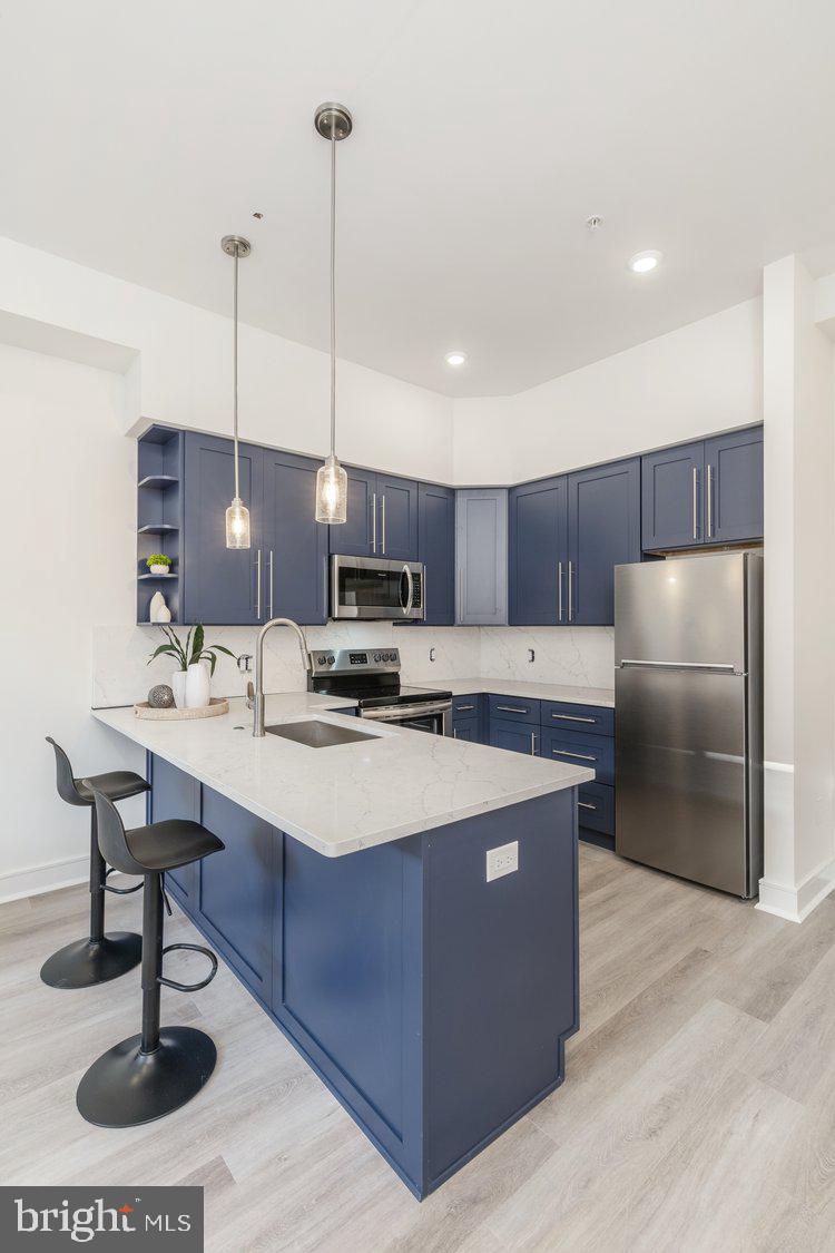 4550 Mitchell Street, Unit 208 Philadelphia, PA 19128 - Photo 2 of 25 a kitchen with stainless steel appliances kitchen island granite countertop a sink a refrigerator and a counter top space