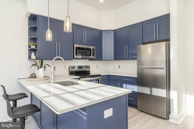 a kitchen with kitchen island a refrigerator a stove a sink and chairs