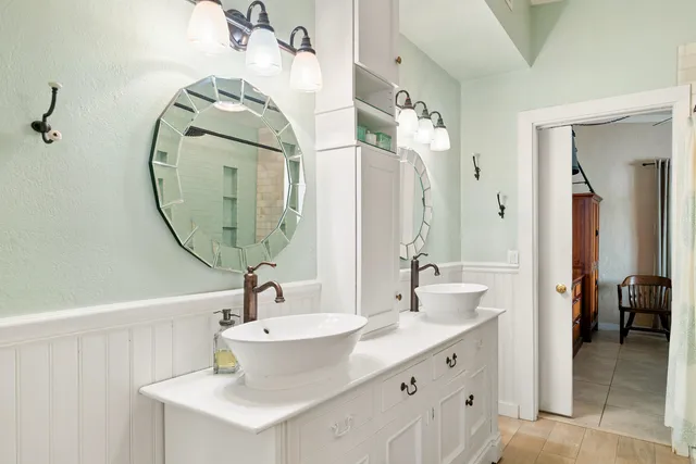 a bathroom with a double vanity sink a toilet a mirror and shower