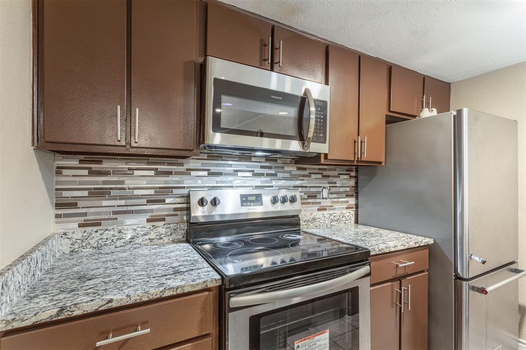 a kitchen with granite countertop a stove microwave and refrigerator
