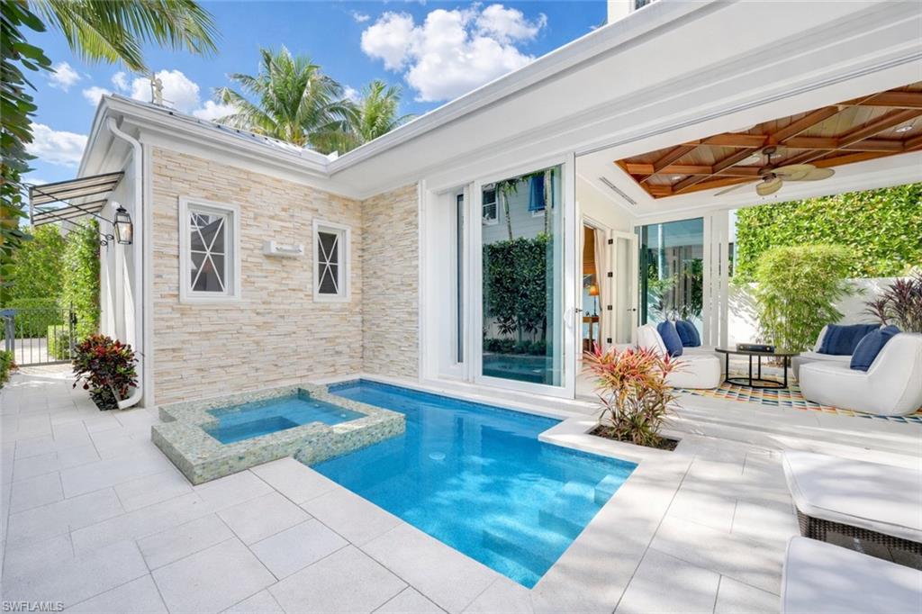 42 6th Street South Naples, FL 34102 - Photo 12 of 46 Rear view of property featuring a patio area, a pool with connected hot tub, ceiling fan, and stone siding