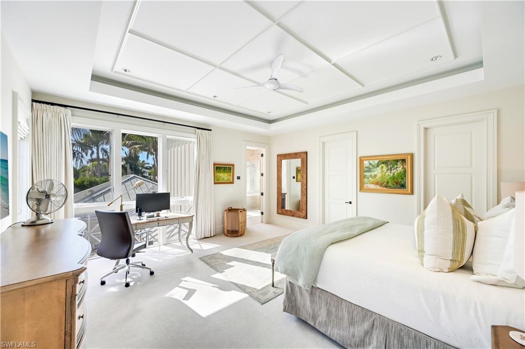 42 6th Street South Naples, FL 34102 - Photo 31 of 46 Bedroom featuring a desk, ensuite bath, a tray ceiling, ceiling fan, and light carpet