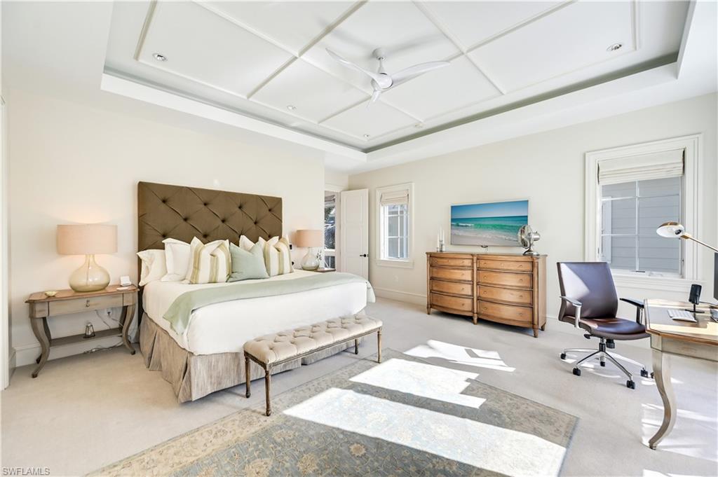 42 6th Street South Naples, FL 34102 - Photo 33 of 46 Bedroom with light colored carpet, a tray ceiling, and an office area