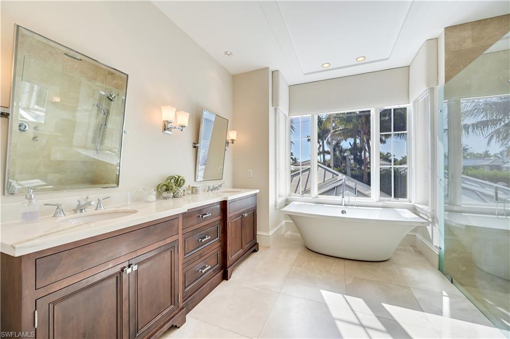 42 6th Street South Naples, FL 34102 - Photo 35 of 46 Bathroom featuring double vanity, a freestanding tub, a shower stall, light tile patterned floors, and recessed lighting