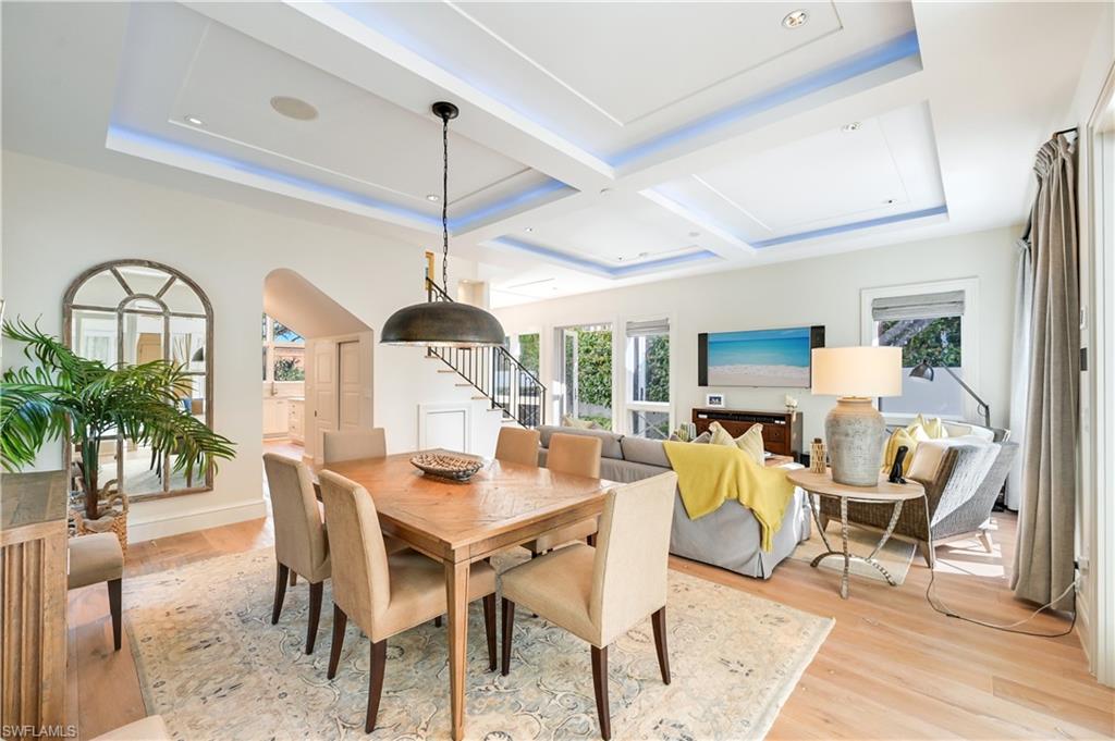 42 6th Street South Naples, FL 34102 - Photo 7 of 46 Dining room with light wood-type flooring, healthy amount of natural light, arched walkways, coffered ceiling, and a raised ceiling