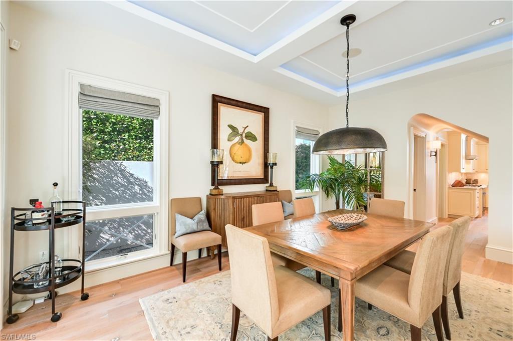 42 6th Street South Naples, FL 34102 - Photo 10 of 46 Dining space featuring arched walkways, light wood finished floors, and a raised ceiling
