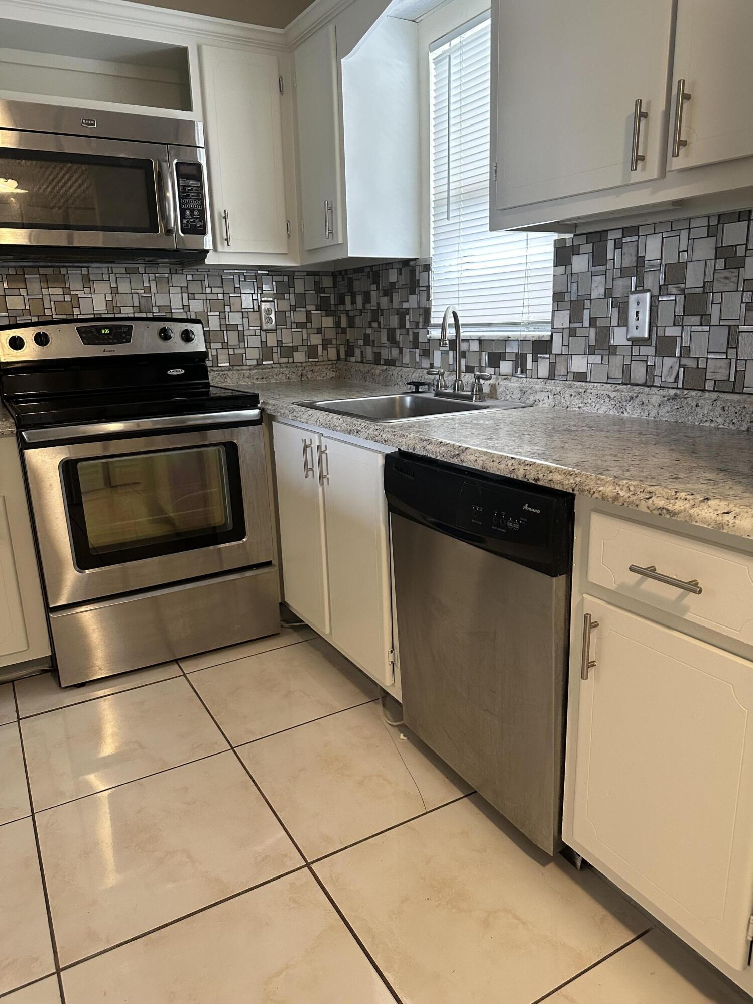 9355 Southwest 8th Street, Unit 311 Boca Raton, FL 33428 - Photo 3 of 17 a kitchen with granite countertop a stove top oven microwave and cabinets
