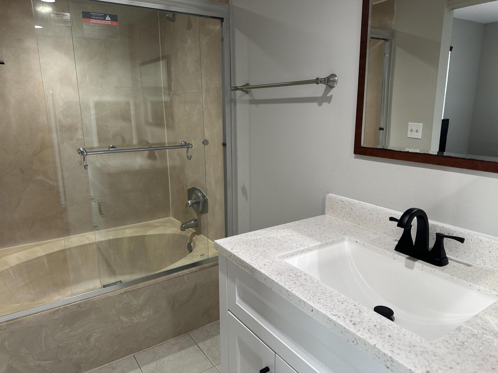 9355 Southwest 8th Street, Unit 311 Boca Raton, FL 33428 - Photo 7 of 17 a bathroom with a sink a mirror and shower
