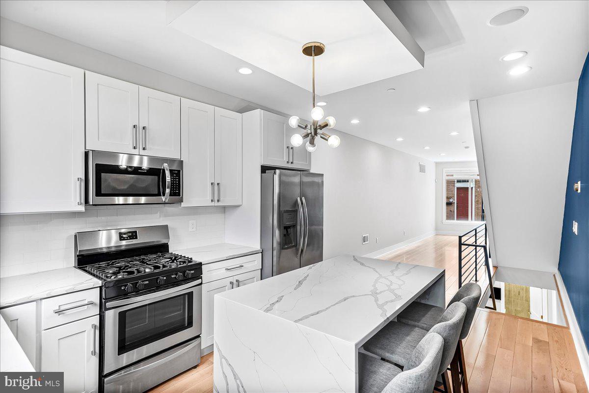 2615 East Letterly Street Philadelphia, PA 19125 - Photo 12 of 36 a kitchen with stainless steel appliances a stove a microwave a refrigerator a stove white cabinets a dining table and chairs