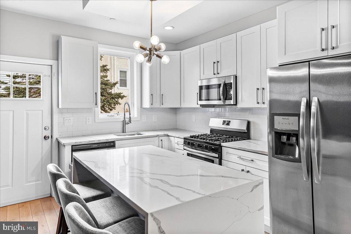 2615 East Letterly Street Philadelphia, PA 19125 - Photo 10 of 36 a kitchen with stainless steel appliances granite countertop a stove a refrigerator a sink a stove and white cabinets