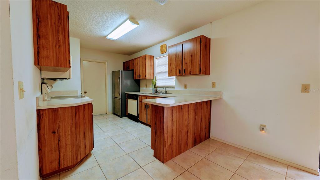 11438 Palomar Street Spring Hill, FL 34609 - Photo 13 of 37 a kitchen with stainless steel appliances granite countertop a stove a sink and a refrigerator