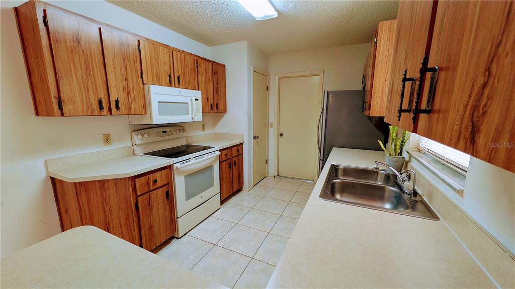 11438 Palomar Street Spring Hill, FL 34609 - Photo 15 of 37 a kitchen with stainless steel appliances granite countertop a stove a sink and a refrigerator