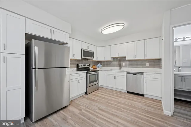 a kitchen with white cabinets stainless steel appliances and a refrigerator