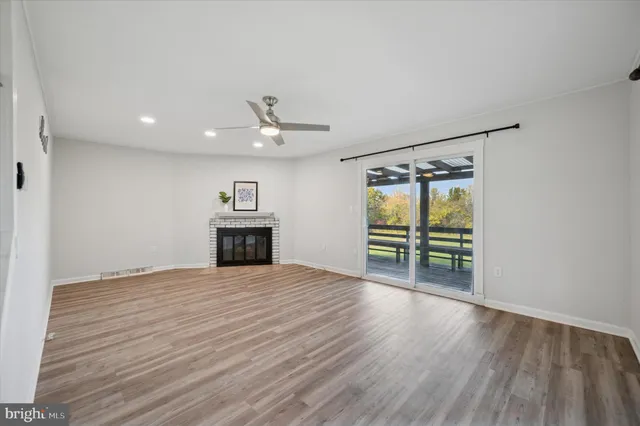 a view of an empty room with a fireplace and wooden floor