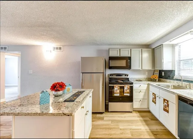 a kitchen with stainless steel appliances granite countertop a stove sink and refrigerator
